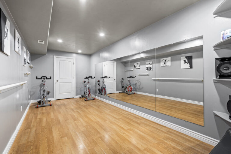 A gym room with a treadmill and a long mirror
