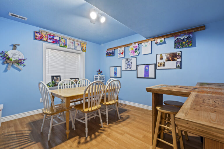 A dining room with blue-painted walls and multiple wall frames