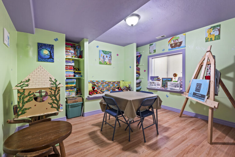 A child's room with books, a table, wall paintings, and more